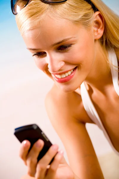 Молодая красивая сексуальная загорелая блондинка с телефоном в бикини — стоковое фото