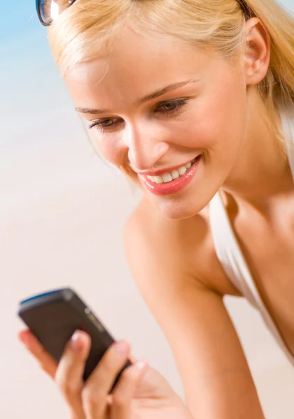 Ung vacker kvinna med mobiltelefon på stranden — Stockfoto