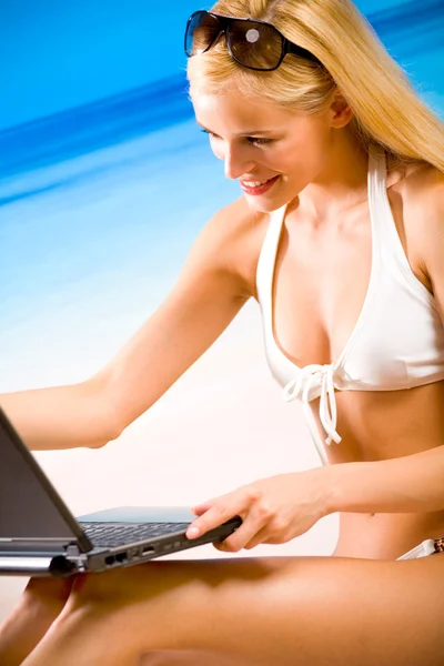Unga vackra kvinnan i bikini med laptop på stranden — Stockfoto