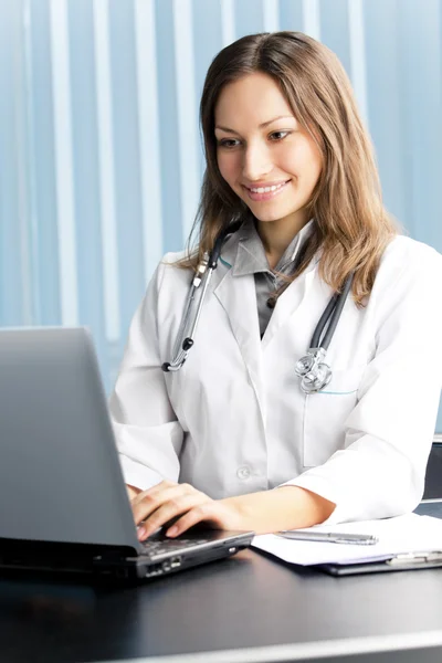 Médico feliz ou enfermeira com laptop no escritório — Fotografia de Stock