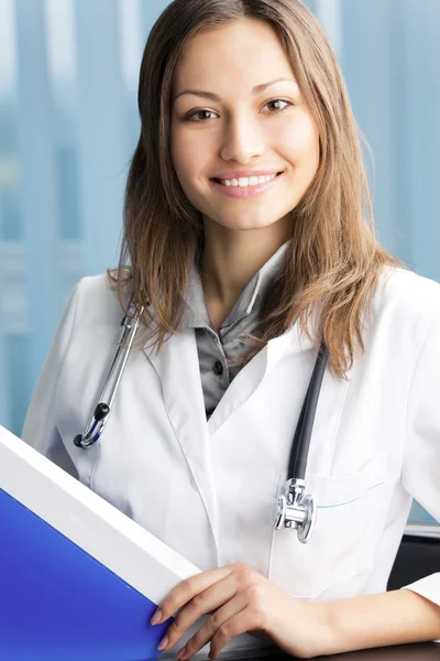 Feliz médico con carpeta azul en el consultorio —  Fotos de Stock