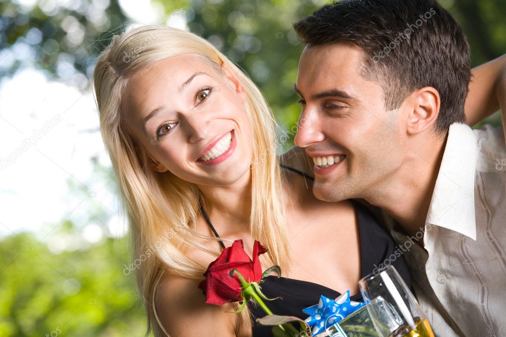 Young happy couple with gifts, rose and champagne outdoors