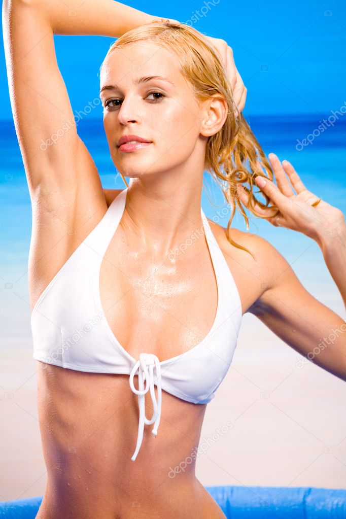 Young sexy beautiful tanned blond warm woman in white bikini on