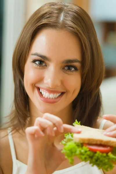 Portrait of young happy woman with sandwich at home — Stock Photo, Image