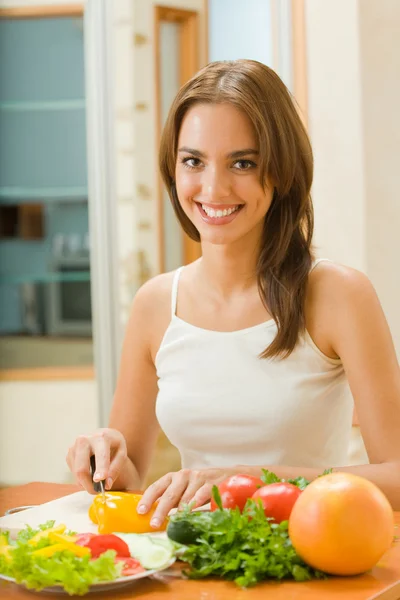Young happy woman making salad at domestic kitchen — Stock Photo, Image