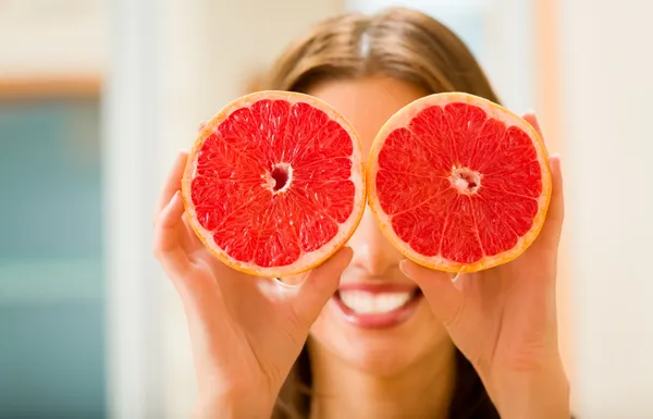 Mladá žena s grapefruity doma — Stock fotografie