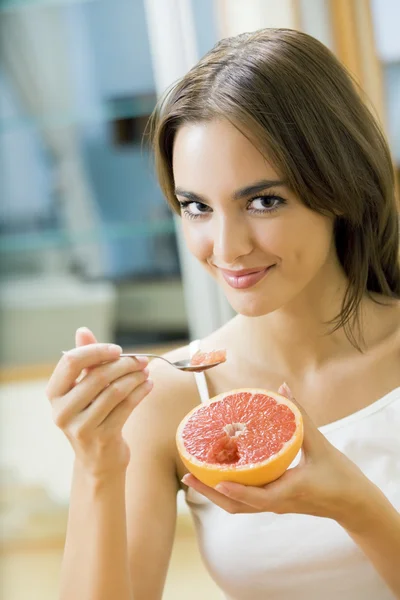 Портарит, где молодая женщина ест грейпфрут дома — стоковое фото