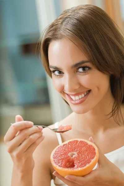 Портрет молодой счастливой женщины, поедающей грейпфрут дома — стоковое фото