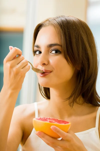 Młoda kobieta, spożywanie grejpfrutów w domu — Zdjęcie stockowe
