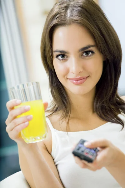 Ung glad kvinna med juice, tittar på tv hemma — Stockfoto