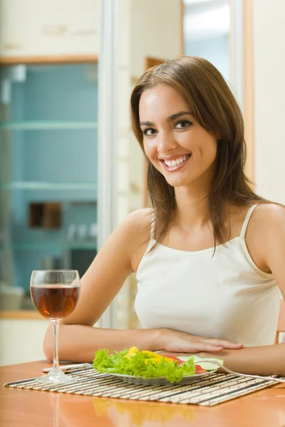 Jeune femme avec verre de vin rouge et salade à la maison Image En Vente