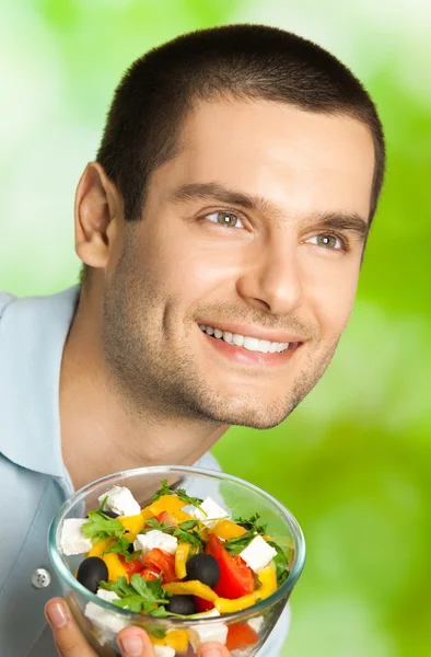Porträtt av ung glad man äta sallad, utomhus — Stockfoto