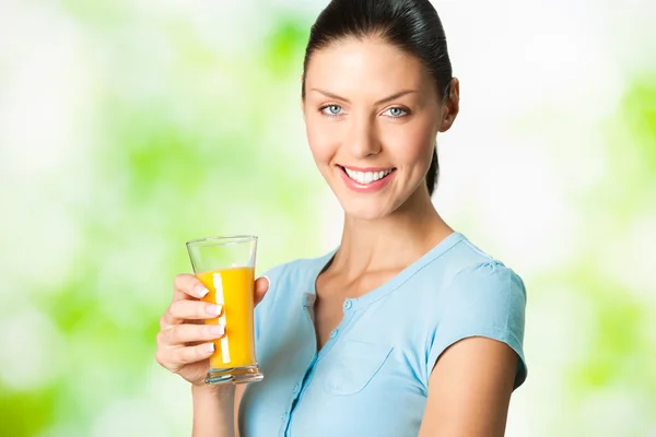 Jovem bela mulher sorridente com vidro de suco de laranja, outdoo — Fotografia de Stock