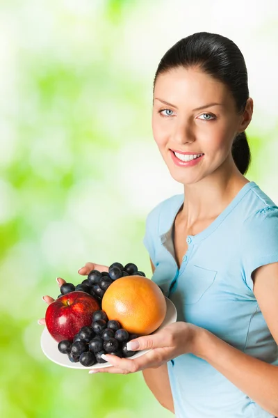 Young happy smiling woman with plate of fruits, outdoor — Stock Photo, Image