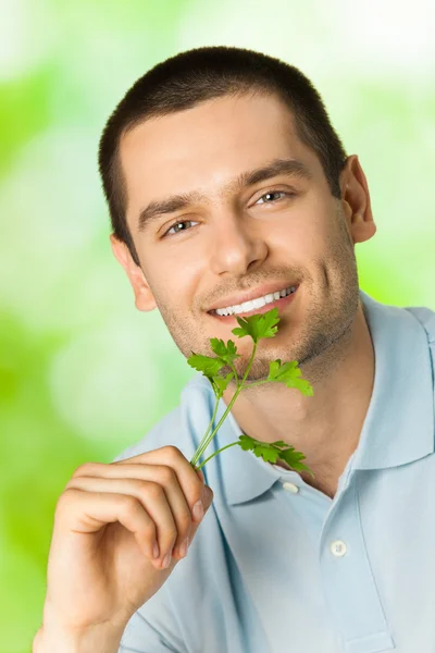Giovane attraente felice uomo sorridente con potherbs, all'aperto — Foto Stock