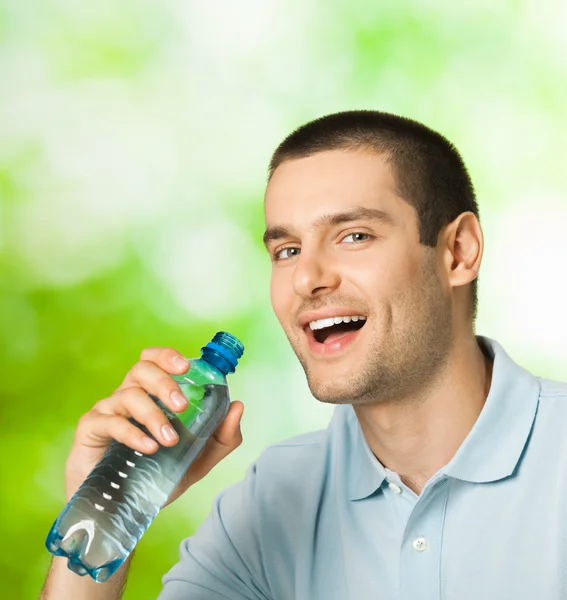 Jonge gelukkig lachende man drinkwater, buitenshuis — Stockfoto
