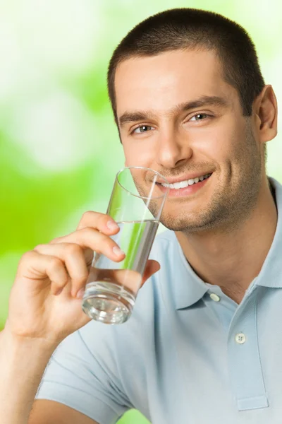 Giovane felice uomo sorridente acqua potabile, all'aperto — Foto Stock