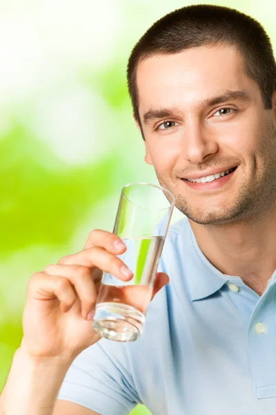 Fiatal, mosolygós ember pohár vízzel, szabadban — Stock Fotó