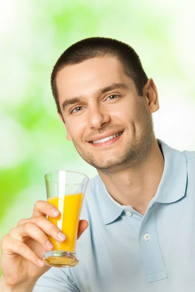 Retrato de jovem feliz sorrindo homem bebendo suco de laranja, outdo — Fotografia de Stock