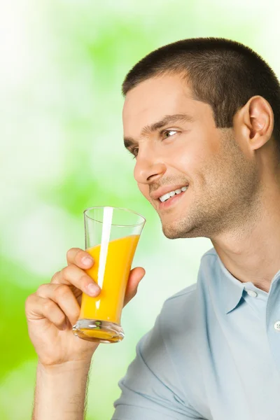 Portret młodego człowieka uśmiechający się zadowolony, picie soku pomarańczowego, prześcignąć — Zdjęcie stockowe