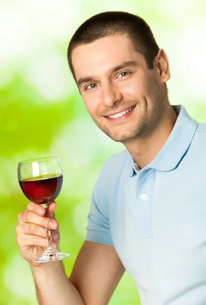 Jonge gelukkig lachende man met rode wijn, buitenshuis — Stockfoto