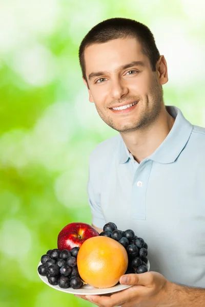 Retrato de joven feliz hombre sonriente con plato de frutas, outdoo — Foto de Stock