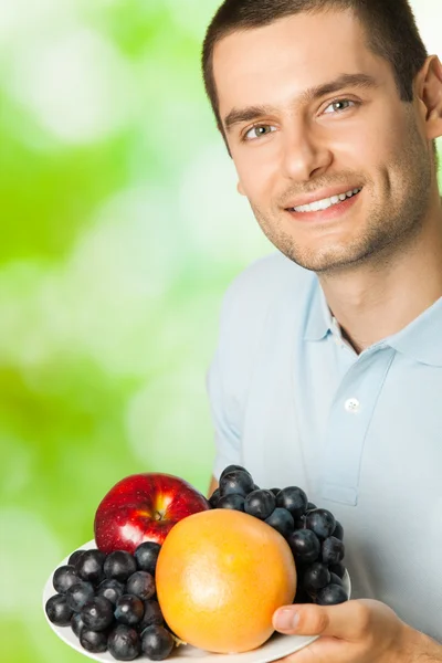 Retrato de joven feliz hombre sonriente con plato de frutas, outdoo —  Fotos de Stock