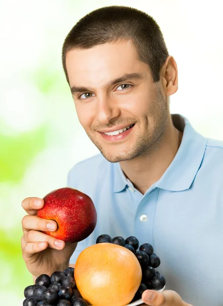 Portrait de jeune homme souriant heureux avec assiette de fruits, outdoo — Photo
