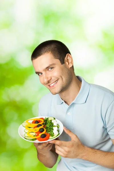 Retrato de joven feliz hombre sonriente con plato de ensalada, al aire libre — Foto de Stock