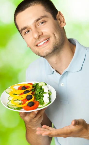 Retrato de joven feliz hombre sonriente con plato de ensalada, al aire libre —  Fotos de Stock