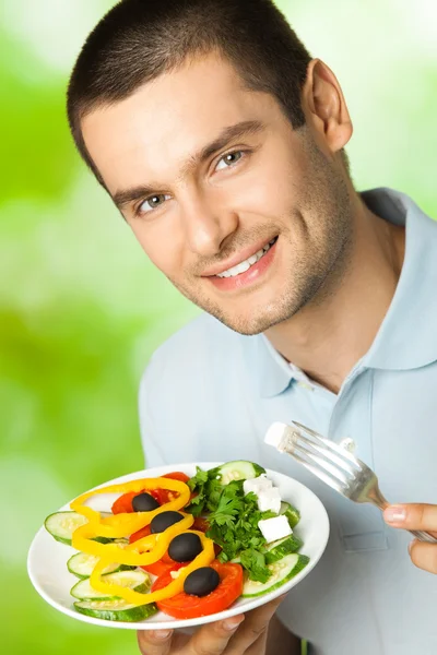 Porträt eines glücklichen jungen Mannes beim Salatessen im Freien — Stockfoto
