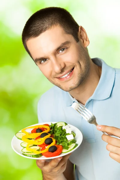 Portret van jonge gelukkig man eten Salade, buitenshuis — Stockfoto