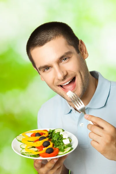 Portrait de jeune homme heureux mangeant de la salade, en plein air — Photo