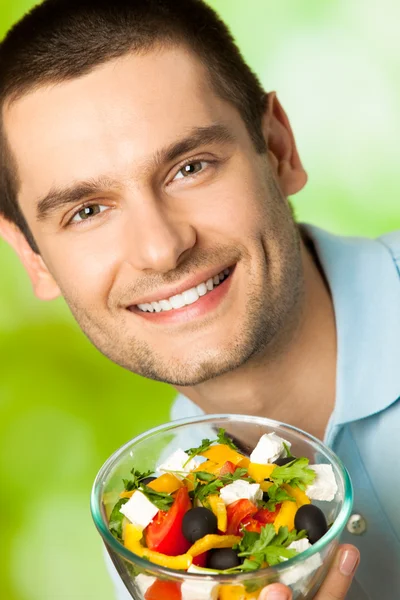 Młody szczęśliwy uśmiechający się człowiek z sałatką, na zewnątrz — Zdjęcie stockowe