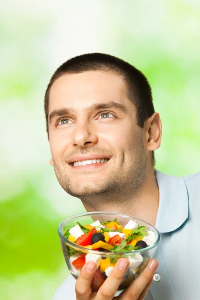 Portret młodego człowieka szczęśliwego, jedzenie sałatki, na zewnątrz — Zdjęcie stockowe