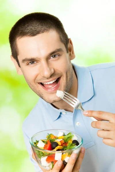 若い幸せな男を食べるサラダ、屋外の肖像画 — ストック写真