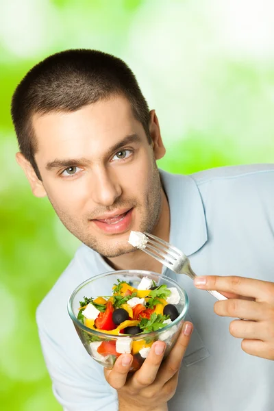 Ritratto di giovane uomo felice che mangia insalata, all'aperto — Foto Stock
