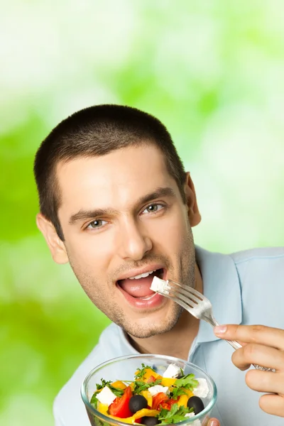 Портрет молодого щасливого чоловіка, що їсть салат, на відкритому повітрі — стокове фото