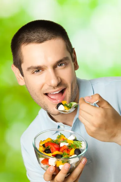 Ritratto di giovane uomo felice che mangia insalata, all'aperto — Foto Stock
