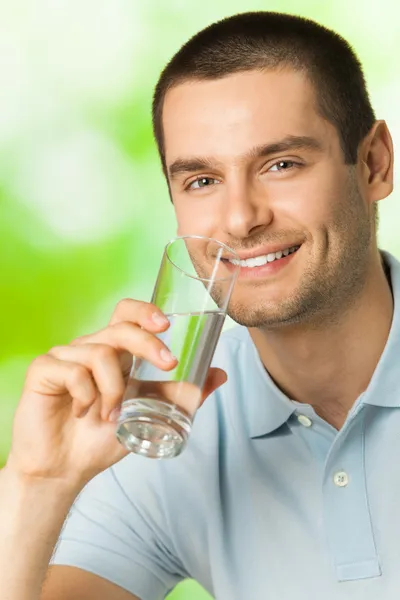 Young happy smiling man drinking water, outdoors Stock Picture