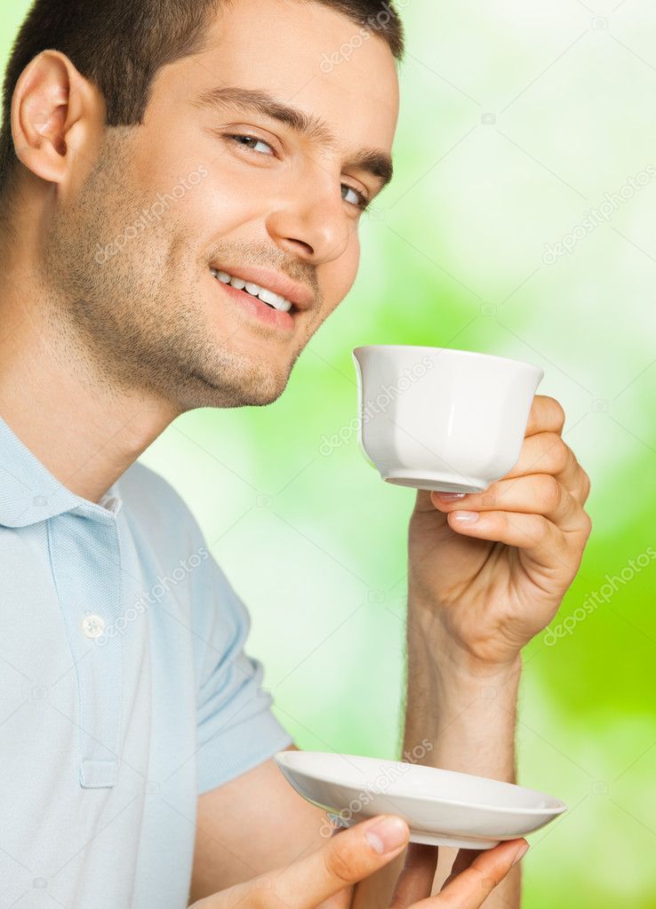 Young happy smiling man with cup of coffee, outdoors