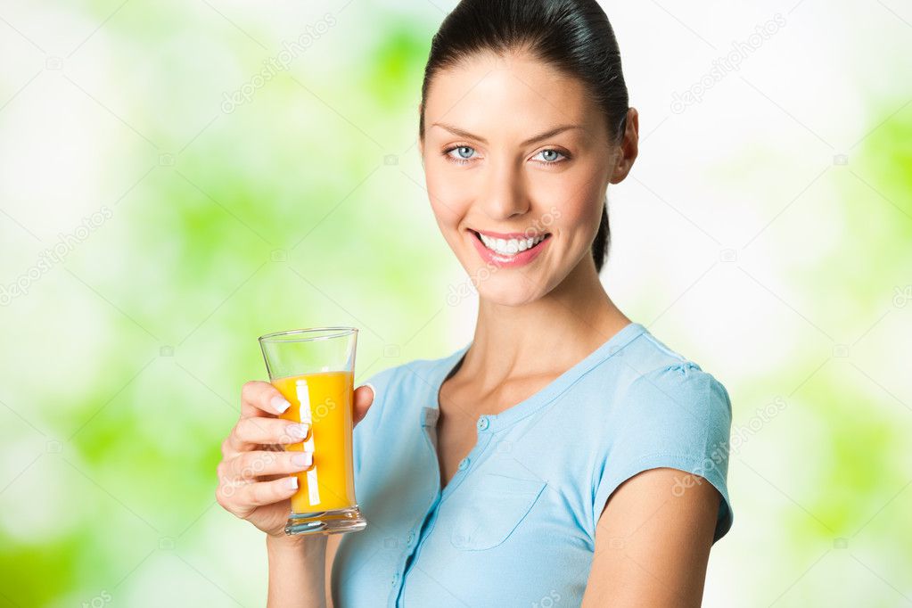 Young beautiful smiling woman with glass of orange juice, outdoo