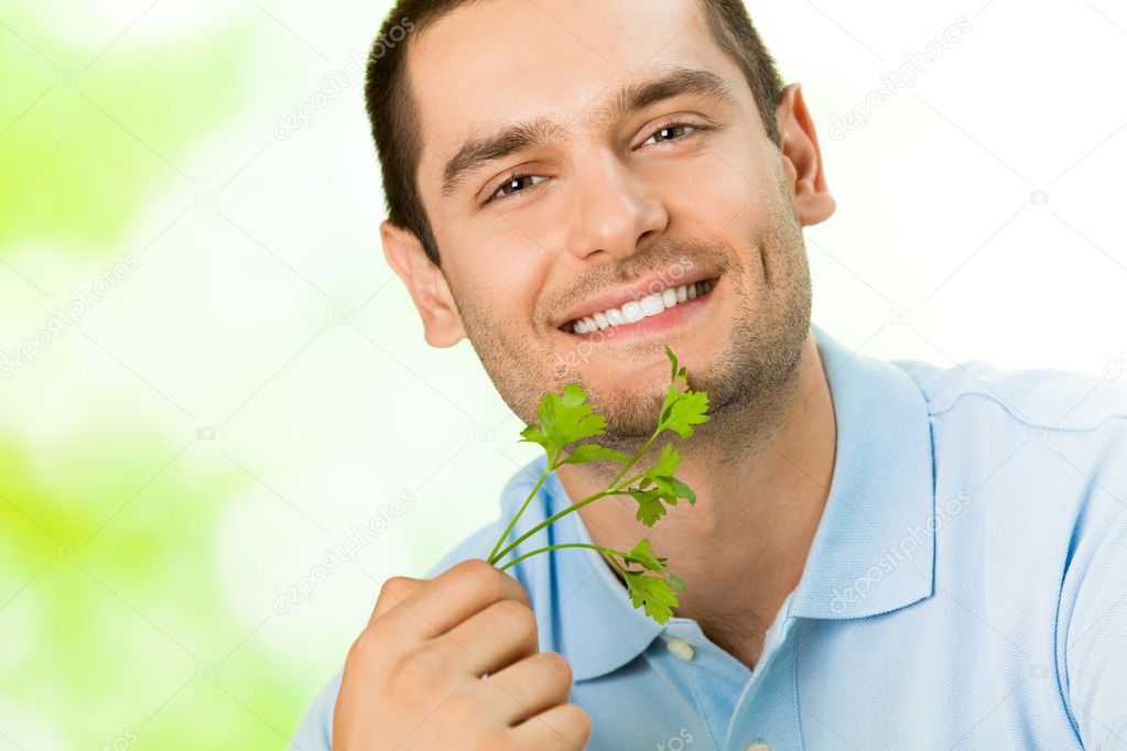 Young attractive happy smiling man with potherbs