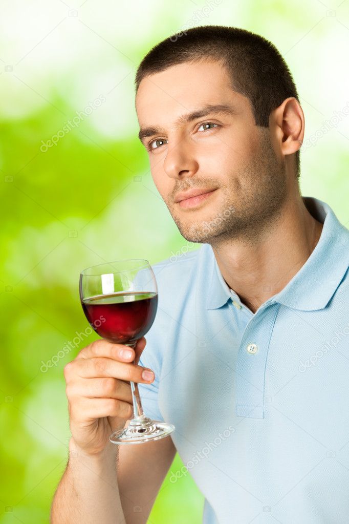 Young man with glass of redwine, outdoors
