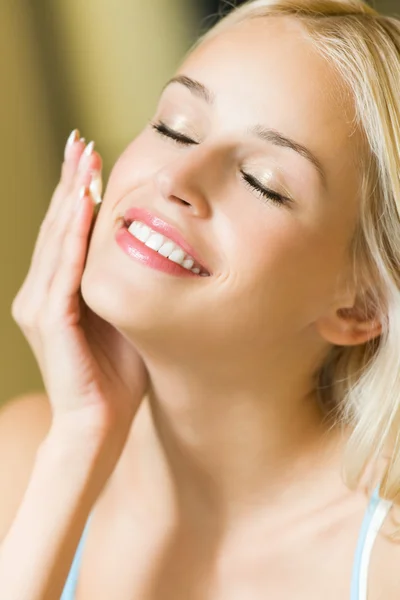 Donna sorridente che applica la crema sul viso a casa — Foto Stock