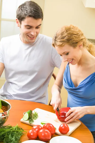 Молодая счастливая пара готовит вместе с овощами дома — стоковое фото