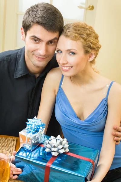 Casal jovem comemorando com champanhe e presentes em casa — Fotografia de Stock
