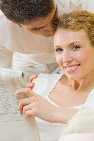 Jovem casal amoroso ler jornal em casa — Fotografia de Stock
