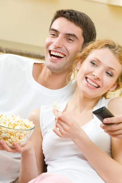 Young couple eating popcorn and watching TV together at home — Stock Photo, Image