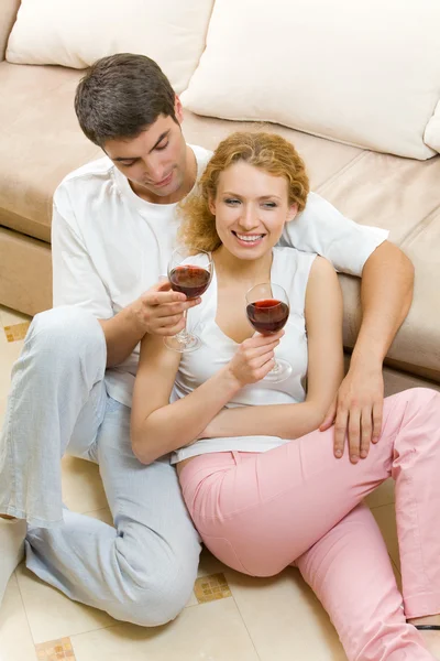 Casal jovem comemorando com vinho tinto em casa — Fotografia de Stock